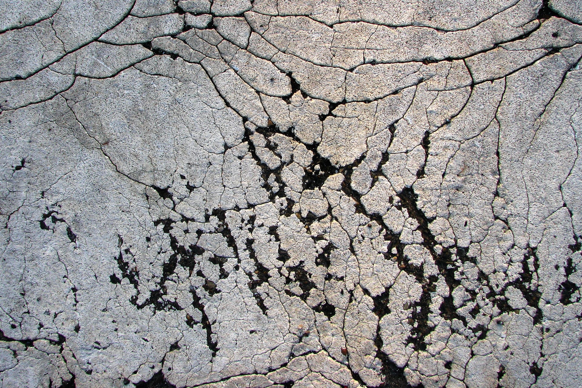 Paviment de formigó molt esquerdat, amb fissures en xarxa i peces despreses.