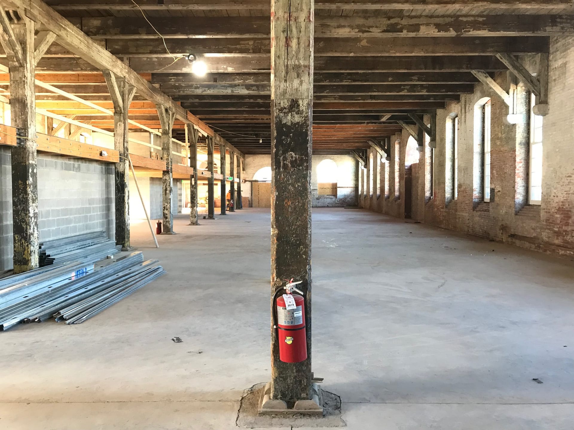 Open interior of an old warehouse with timber posts and beams and a concrete floor.
