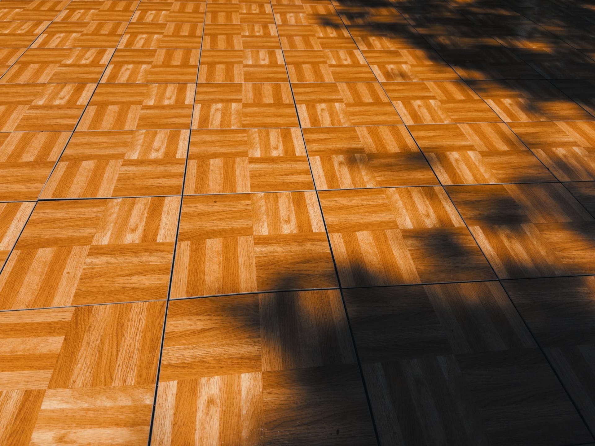 Suelo de parquet de lamas en damero iluminado por la luz y las sombras.