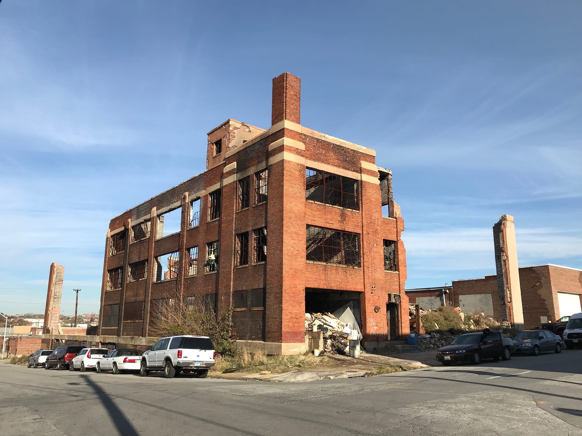 Brick industrial building gutted by fire, roofless and with empty window openings.