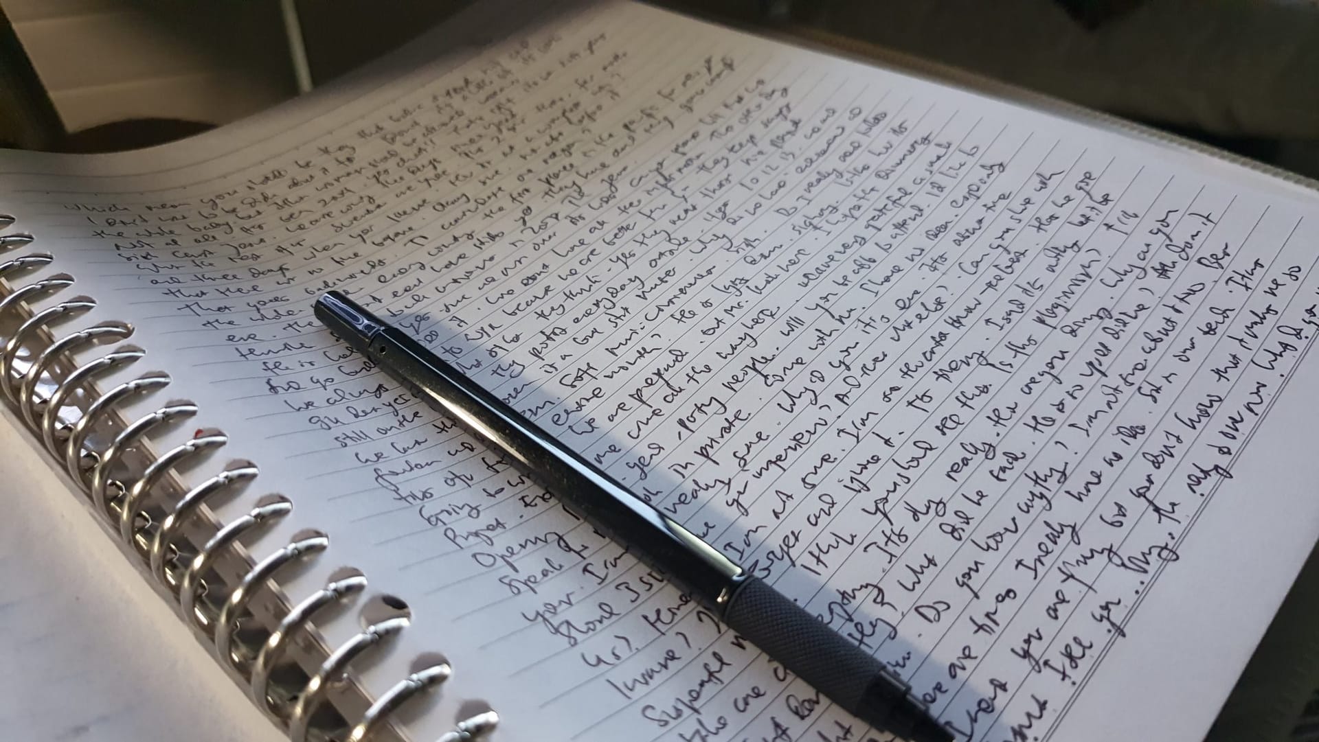 Spiral notebook with handwritten notes and a pen on top.